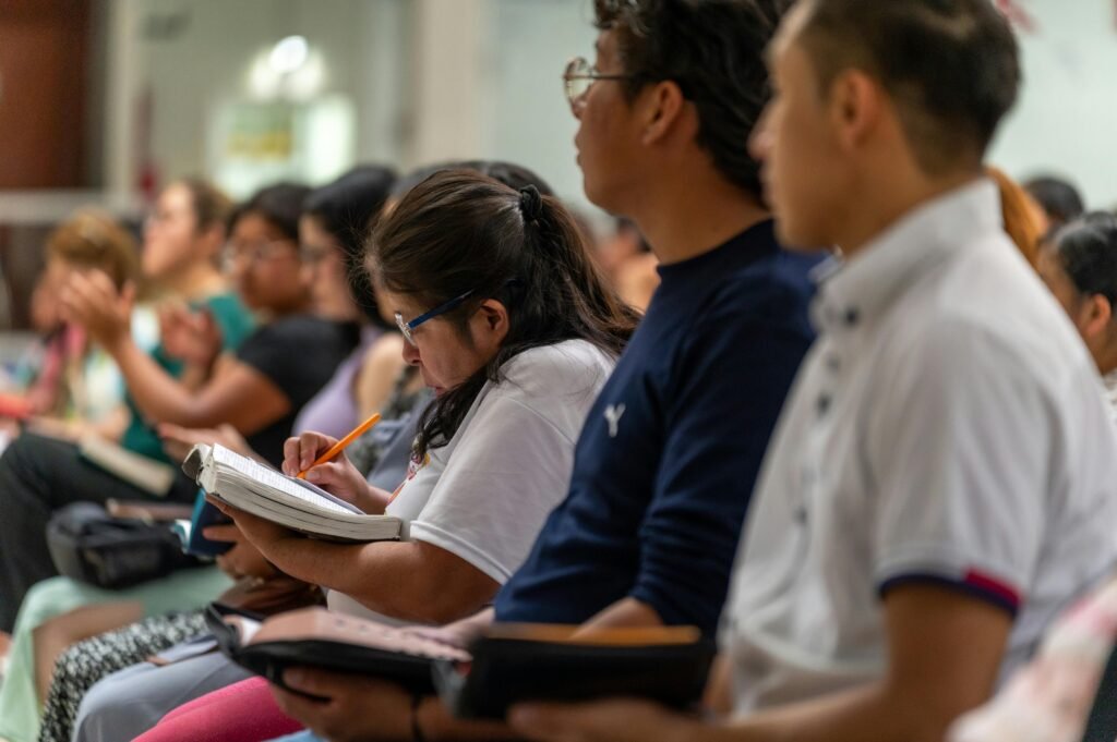 Adults sitting in a religious gathering, engaged in note-taking and worship in Mexico.