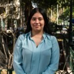 Portrait of a young woman standing in a sunlit park in Piura, Peru.